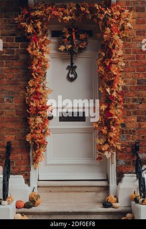 Rye, UK - October 10, 2020: Close up of orange leaves and pumpkins Halloween decorations by the entrance to house in Rye, one of the best-preserved me Stock Photo