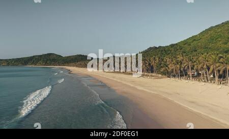 Waves washed sand ocean coast aerial. Tropical forest at paradise island. Nobody tropic nature seascape of El Nido Island, Philippines, Asia. Palm trees with lodges at sea bay Stock Photo