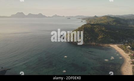 Sun seascape at mist fog aerial. Tropical nobody nature landcape at rural buildings. Green forested hillside village at sea bay. Mountains with palm trees at misty haze. Cinematic soft sunlight Stock Photo