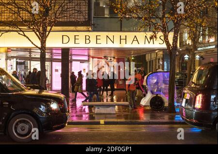 Debenhams department store on Oxford Street in the rain. Shoppers walking along doing their Christmas shopping. London Stock Photo