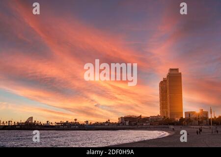 sunset over barceloneta beach in barcelona, spain, during winter with cloudy sky. calm and peaceful sea waves. nobody. twilight time at dusk with skys Stock Photo