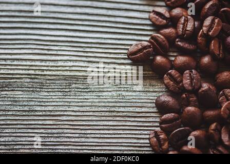 weathered wooden background with roasted coffee beans on side, copy space Stock Photo