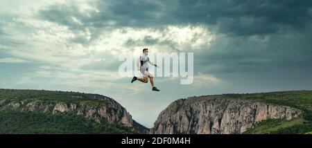 banner of man jumping between cliffs success concept Stock Photo