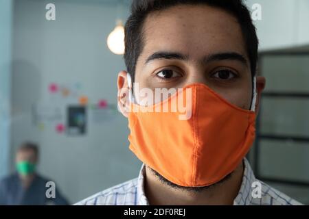 Portrait of mixed race man wearing mask in an office Stock Photo