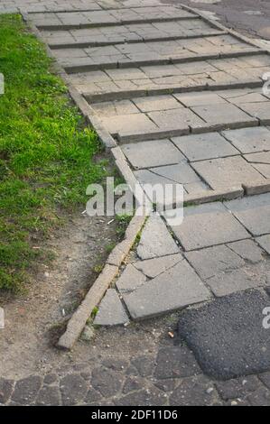 An uneven concrete brick path beside grasses Stock Photo