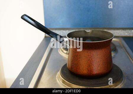 An closeup of an old copper pot with a spout on a stove Stock Photo