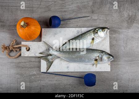 Raw Bluefish. (Latin; Pomatomus Saltatrix). Fresh fish with the vegetables, condiment and lemon, bluefish. Food preparation. Stock Photo