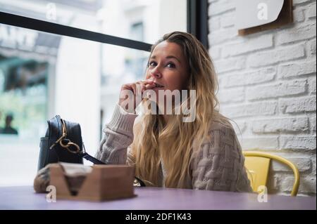 thoughtful woman sitting in cafe with a bag on the table and thinking about a plan for the future Stock Photo