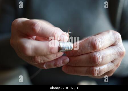 Close up of an old woman threading a needle Stock Photo