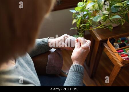 Old woman mending a sock at home Stock Photo