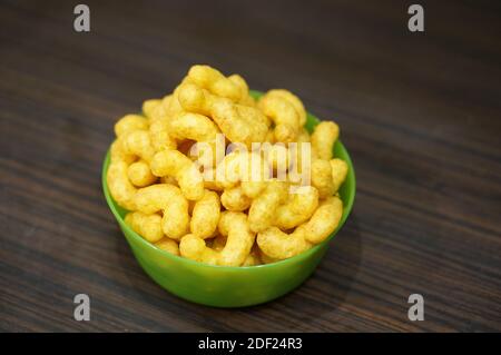Many yellow corn puffs in a green bowl Stock Photo