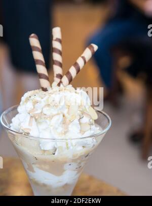 A closeup shot of ice cream shake desert topped with almond nuts and wafer sticks Stock Photo