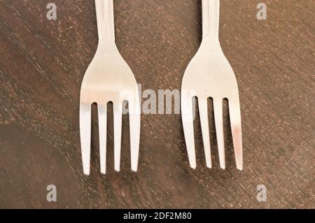 A closeup shot of two white plastic forks on a wooden surface Stock Photo