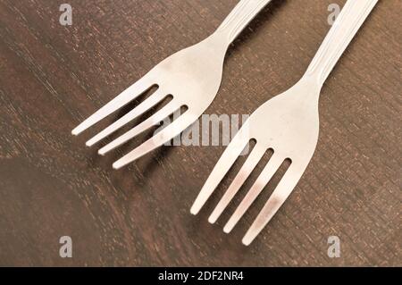 A closeup shot of two white plastic forks on a wooden surface Stock Photo