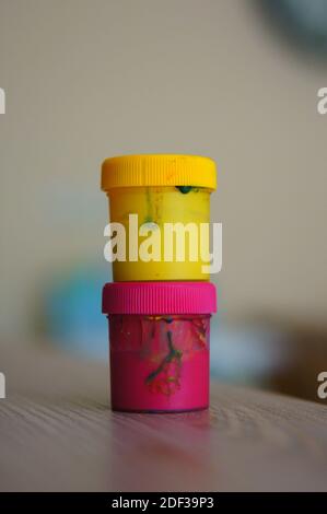 The color gouache jars on top of each other on a wooden table in the room Stock Photo