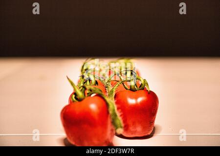 Cherry tomatoes on white table and black background Stock Photo