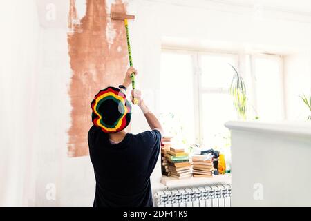Painter woman painting the wall in home, with paint roller and brown color paint. Room renovations at house concept. Stock Photo