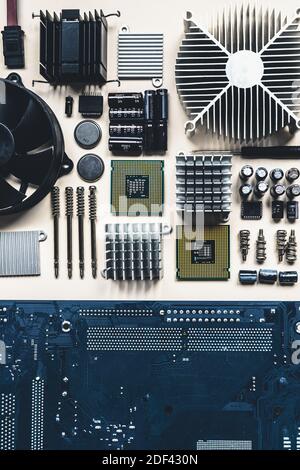 Top view of computer parts with CPU, fan cooler, battery, capacitors, radiator, chip, screwdrivers on white table background with copy space. DIY constructor concept. Stock Photo