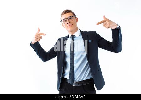 Confident businessman in glasses and suit, man shows his fingers on himself standing isolated on white background. A handsome businessman is glad that Stock Photo