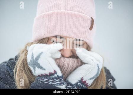 Female closing here eyes and warming up her hands on a very cold day. Stock Photo