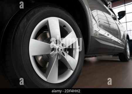The rear of a shiny new car with a wheel in the foreground. Stock Photo