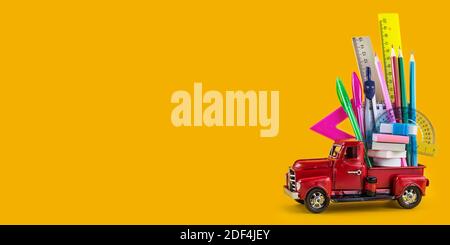 Back to school sale background. Car delivering School stationery on yellow background. Composition with different school stationery on color backgroun Stock Photo