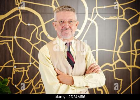 Portrait of positive middle-aged businessman folding arms and looking at camera Stock Photo