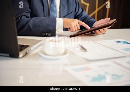 Hands of mature businessman checking document on tablet computer when working on annual report Stock Photo