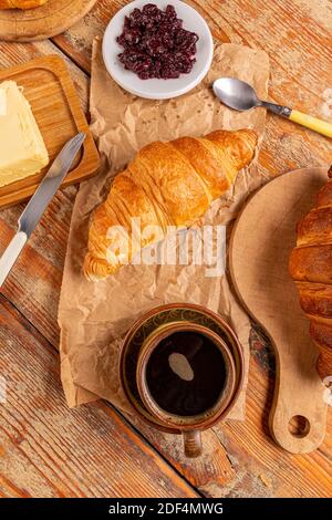 Cup of coffee and croissant, breakfast idea on rustic wooden board Stock Photo