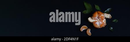 Fresh Mandarin fruit with green leaves isolated on a black background. Banner. Stock Photo