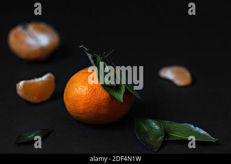 Fresh Mandarin fruit with green leaves isolated on a black background Stock Photo