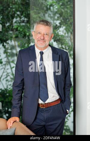 Portrait of smiling mature entrepreneur in glasses standing at leather armchair and looking at camera Stock Photo