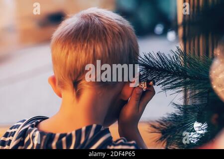 Cute little kid playing with lights on Christmas tree decoration, back view Stock Photo