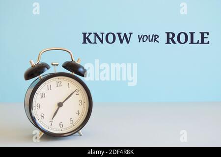 Writing note showing Know Your Role. Business photo showcasing end acting outside who you actually are Play your position. Alarm clock beside a Paper Stock Photo