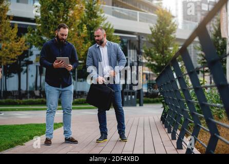 Young businessmen standing with tablet and discussing about plans for the future of the company Stock Photo