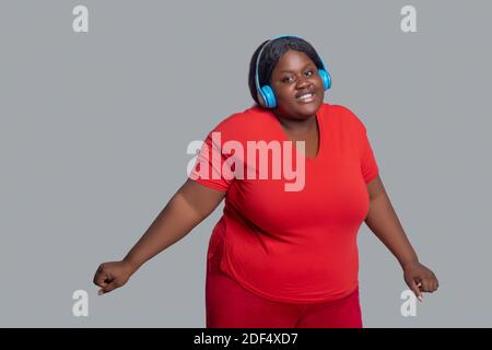 Young dark-skinned woman with headphones feeling energized Stock Photo