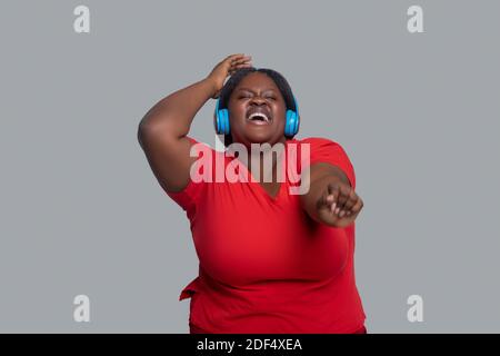 Young dark-skinned woman with headphones feeling energized Stock Photo