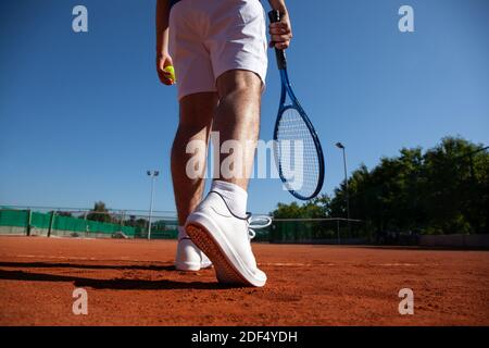 Young tennis player with racket and ball in hands preparing to perform first service in the game Stock Photo