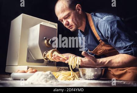Pastaiolo chef making stripes of fresh fettuccine pasta dough. Stock Photo