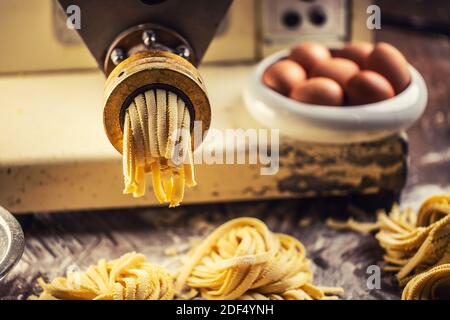 End of pasta making process with fresh fettuccine leaving the pasta maker. Stock Photo