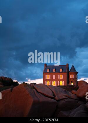 House near lighthouse of Ploumanach (Brittany, France) on a colorful, cloudy evening in summer