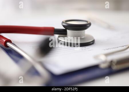 Red stethoscope lying on documents in clipboard in clinic closeup Stock Photo