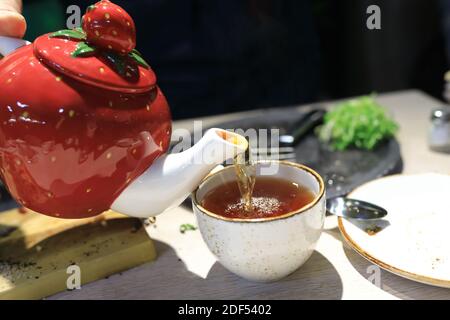 Person pouring black tea in a restaurant Stock Photo