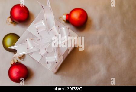 Flat lay composition of small gift box with defocused orange and green Christmas balls around it. Stock Photo