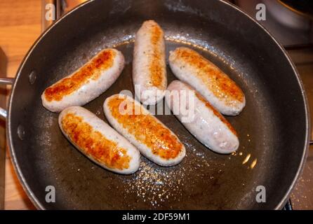 Browning off frying pork sausages in a frying sauce pan Stock Photo