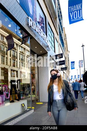 London, England, UK. Woman wearing face mask and headphones in Oxford Street during the COVID pandemic, 2020 Stock Photo