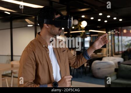 Mixed race businessman wearing virtual reality headset in creative office Stock Photo