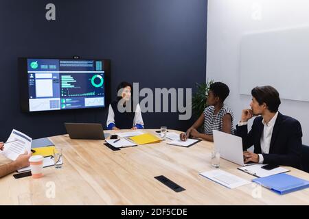 Diverse business people in conference room discussing using laptop computers Stock Photo