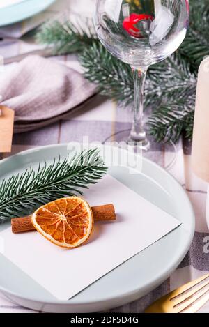 Festive Christmas and New Year details table setting with dry orange and cinnamon on a gray textile. Dining place decorated Stock Photo