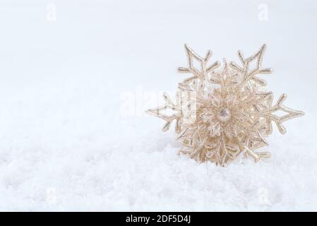 Gold Christmas decoration. Beautiful snowflake on snow background. Winter holidays concept Stock Photo